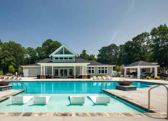 a swimming pool with lounge chairs and a club house in the background