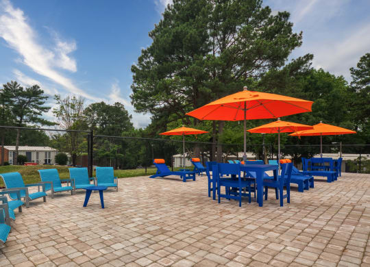 a patio with blue chairs and orange umbrellas and a table and chairs