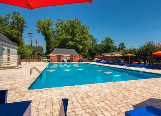 our resort style swimming pool is surrounded by lounge chairs and umbrellas