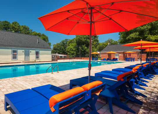 a swimming pool with blue tables and umbrellas next to a house