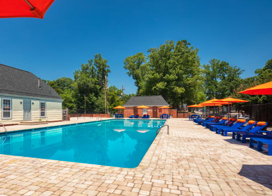 our resort style swimming pool is surrounded by lounge chairs and umbrellas