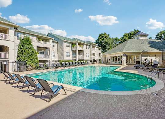 A large swimming pool surrounded by lounge chairs and a gazebo-like structure.