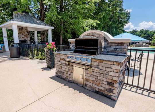 A stone oven is in the middle of a concrete area.