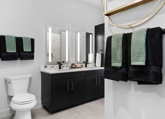 a bathroom with black and green towels and a white toilet