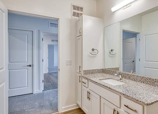A bathroom with a granite countertop and white cabinets.