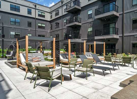 A patio with chairs and tables is in front of a building.