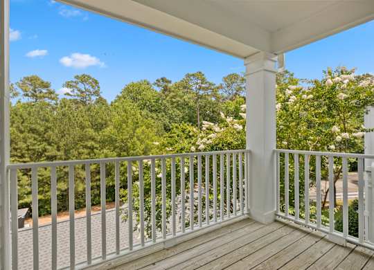 A white porch with a white railing and a view of trees.