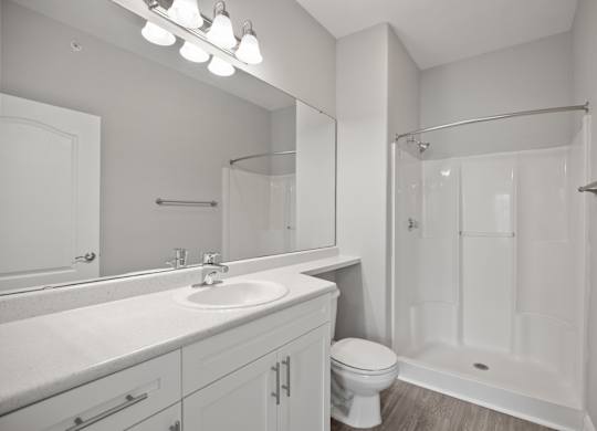 A white bathroom with a sink, toilet, and shower.