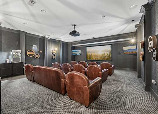 A home theater with a row of brown leather chairs.
