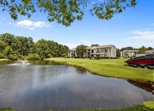 a pond with a boat in front of a building with a fountain