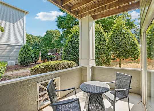A patio with a table and two chairs overlooking a garden.