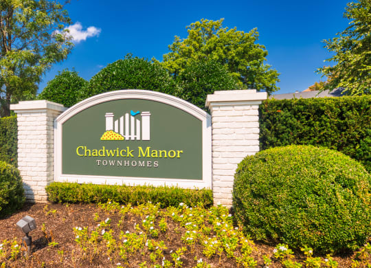 a sign that says chadwick manor townhomes in front of bushes and trees