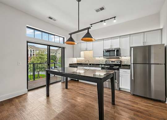 A modern kitchen with a black table and stainless steel appliances.