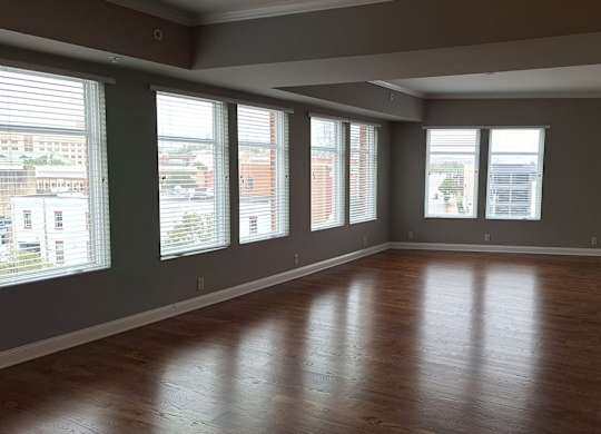 an empty living room with wood floors and windows