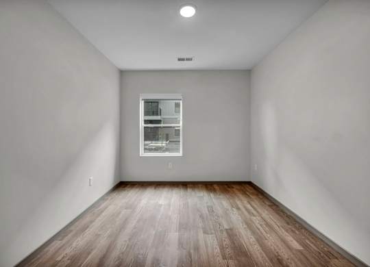 A room with a window and wooden flooring.