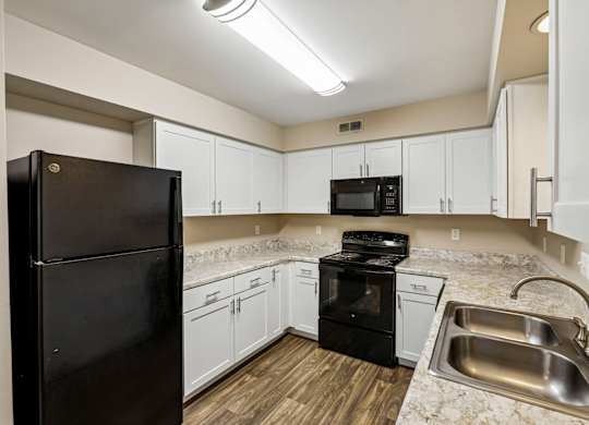A kitchen with black appliances and white cabinets.