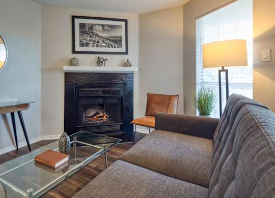A living room with a fireplace, a brown couch, and a glass coffee table.