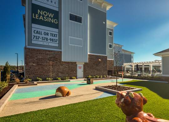 A leasing sign in front of a building with a pool and a statue of a dog.