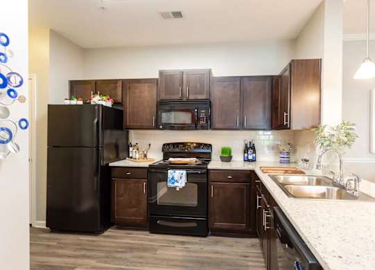 A kitchen with black appliances and brown cabinets.