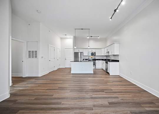 A kitchen with white cabinets and a wooden floor.