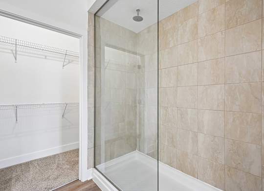A bathroom with a walk-in shower and a glass door.