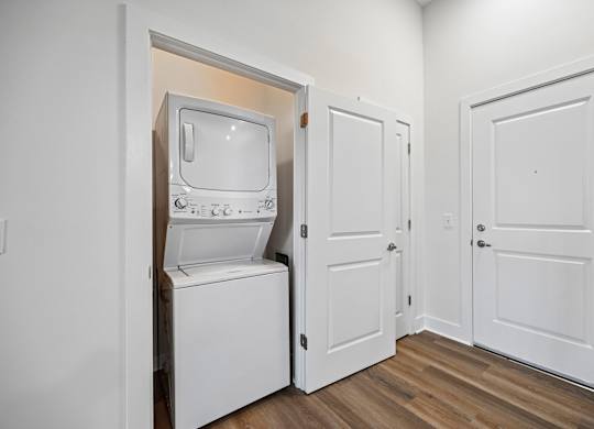 A white vintage television set is sitting in a small room with two doors.
