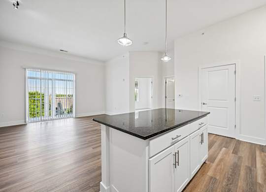 A kitchen with white cabinets and a black countertop.