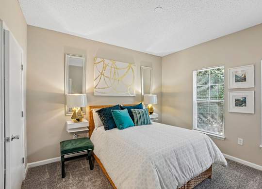 A bedroom with a bed, nightstand, and window.