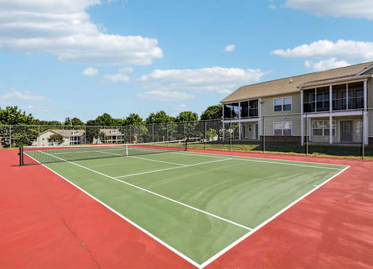 A tennis court with a red surface and white lines.