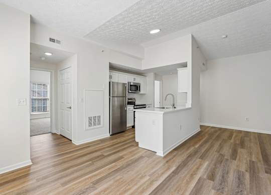A kitchen with white cabinets and a wooden floor.