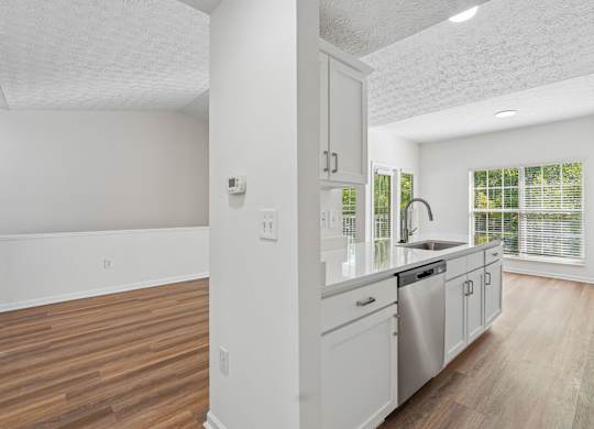 A kitchen with white cabinets and a stainless steel dishwasher.