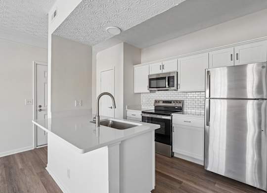 A kitchen with white cabinets and a stainless steel refrigerator.