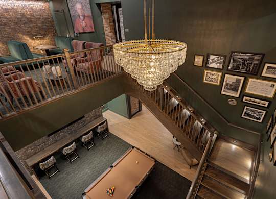 A large chandelier hangs from the ceiling in a room with a staircase.