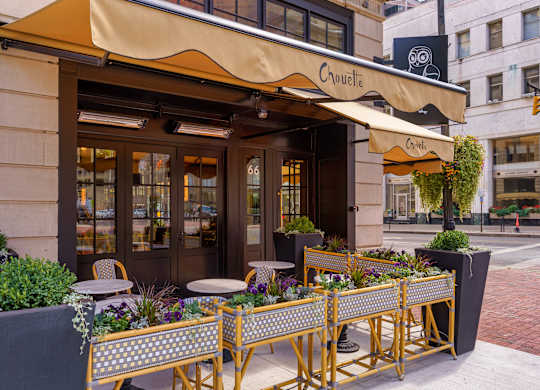 A restaurant named Chouette has a yellow awning and a table set up outside at The Madison in Columbus, OH 43215