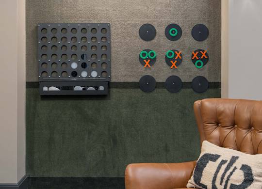 A brown leather chair with a pillow on it in front of a wall with a green board and some circles on it at Orleans Apartments, OH, 43221