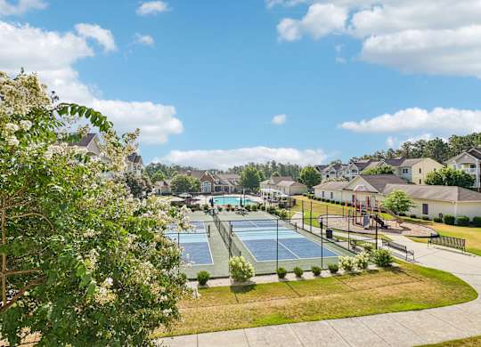 A tennis court is surrounded by houses and trees.