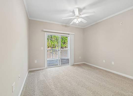 A room with a ceiling fan and a door leading to a balcony.