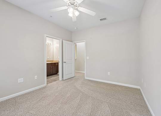 A room with a carpeted floor and a ceiling fan.