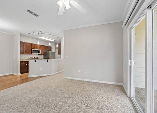 A spacious living room with a sliding glass door leading to a deck.