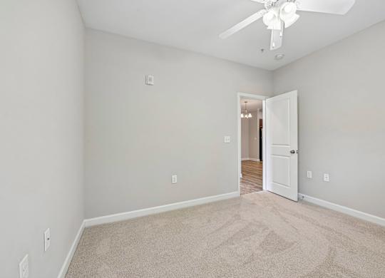 A room with a carpeted floor and a ceiling fan.