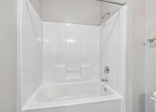A white bathroom with a tub and toilet.