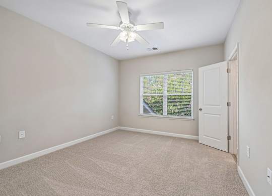 A room with a ceiling fan and a window with blinds.