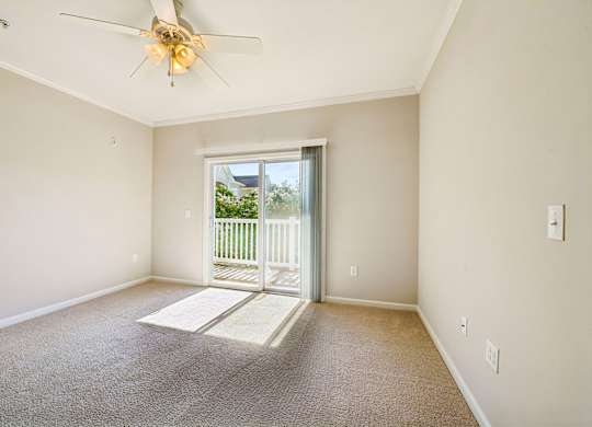 A room with a ceiling fan and a door leading outside.