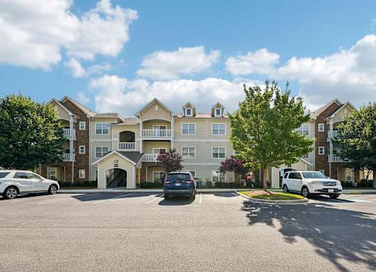 A large apartment complex with cars parked in front.