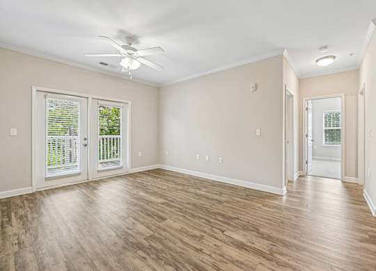 A room with a ceiling fan and sliding glass doors.