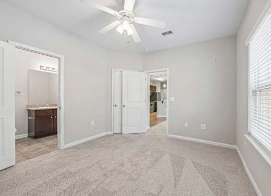 A room with a carpeted floor and a ceiling fan.