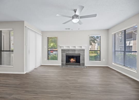 an empty living room with a fireplace and a ceiling fan