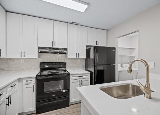 an empty kitchen with white cabinets and black appliances