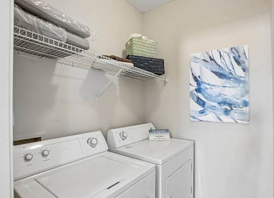 A laundry room with a washer and dryer and a painting on the wall.