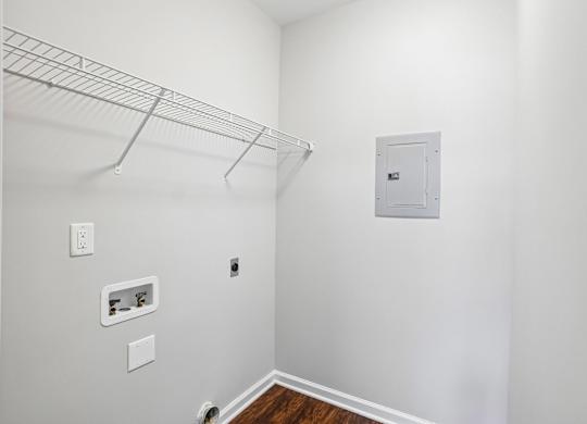 A white wall with a white door and a white shelf.